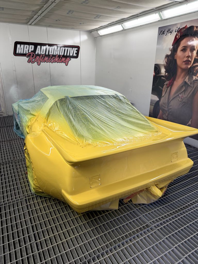 Fresh yellow paint on a masked RX-7 race car in the MRP Automotive downdraft spray booth — Redland Bay
